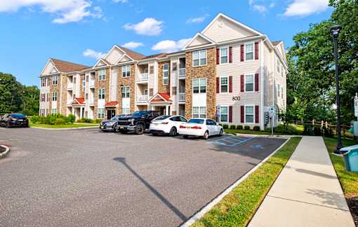 a large apartment building with cars parked in front of it at The Landing Apartment , New Jersey