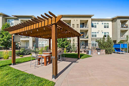 a patio with a pergola and tables in front of an apartment building
