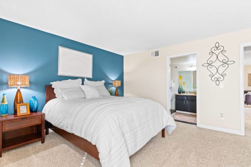 a bedroom with a bed and a blue wall and a bathroom at Silver Reef Apartments, Lakewood, Colorado