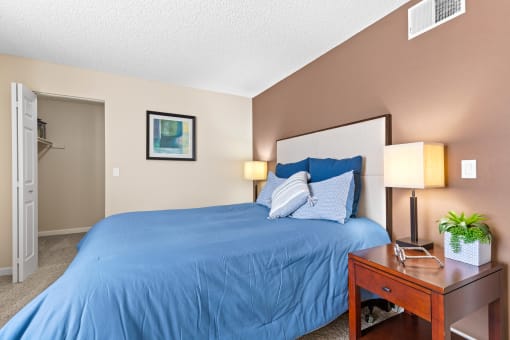 a bedroom with a blue bed and a night stand at Silver Reef Apartments, Lakewood, CO, 80228