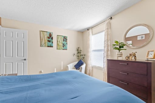 a bedroom with a bed and a dresser and a window at Silver Reef Apartments, Lakewood