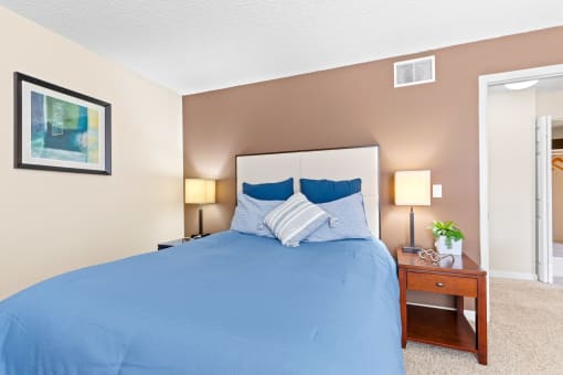 the master bedroom has a large bed and a nightstand with a plant at Silver Reef Apartments, Lakewood, Colorado