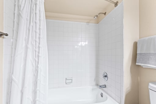 a bathroom with a shower and a tub and a sink at Silver Reef Apartments, Lakewood, 80228