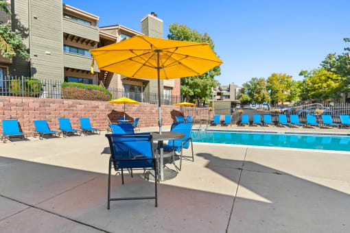 our apartments have a pool and a patio with chairs and an umbrella at Silver Reef Apartments, Lakewood