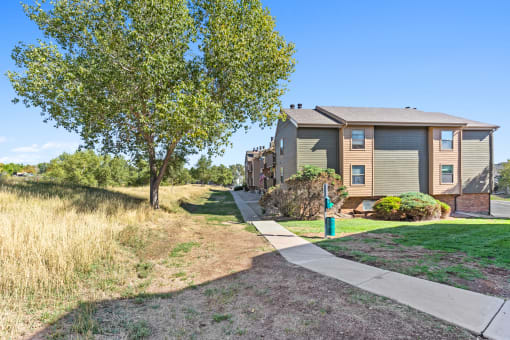 a house with a sidewalk and trees in front of it at Silver Reef Apartments, Lakewood, 80228