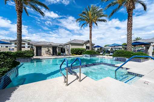 A swimming pool surrounded by palm trees and residential houses. at Vistoria At Country Place Apartments, Arizona, 85353