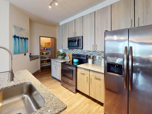 A modern kitchen with a stainless steel refrigerator and wooden cabinets. at Centre Pointe Apartments, Melbourne, Florida