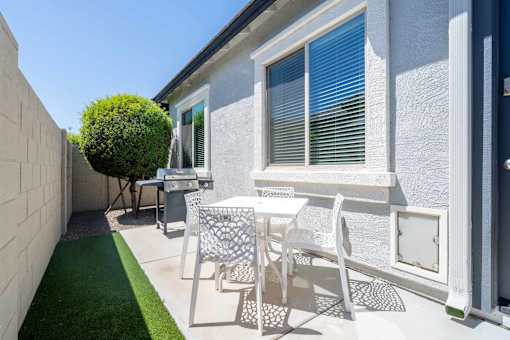 A patio with a table and chairs is set up outside a house at Vistoria At Marley Park Apartments, Surprise, AZ, 85379