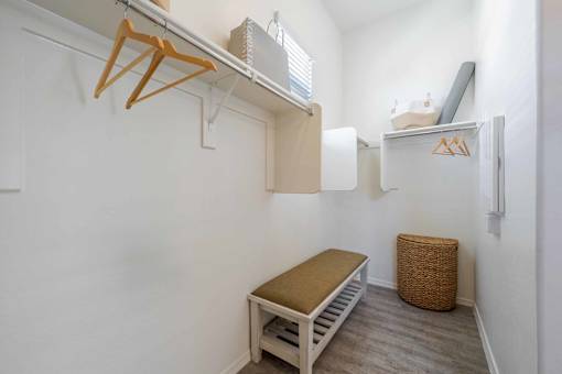 A small room with a bed, a bench, and a small refrigerator. at Vistoria At Marley Park Apartments, Surprise, 85379