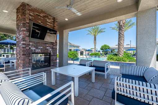 A patio with a brick fireplace and striped couches at Vistoria At Marley Park Apartments, Surprise, AZ, 85379