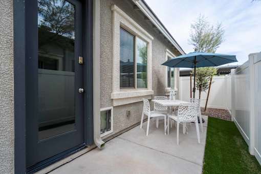 A patio with a table and chairs and an umbrella.