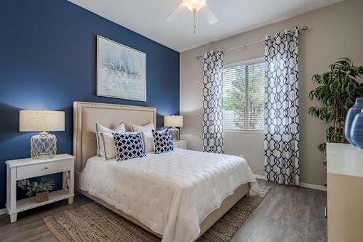A bedroom with a bed, nightstand, and a painting on the wall.