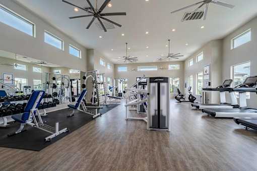 A spacious gym with a variety of equipment and a ceiling fan.