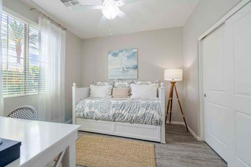 A bedroom with a bed, a table, and a painting on the wall. at Vistoria At Country Place Apartments, Arizona, 85353
