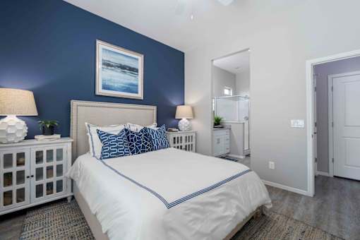 A bedroom with a white bed and blue accents. at Vistoria At Country Place Apartments, Tolleson, AZ, 85353