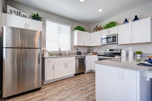 A kitchen with white cabinets and a stainless steel refrigerator.
