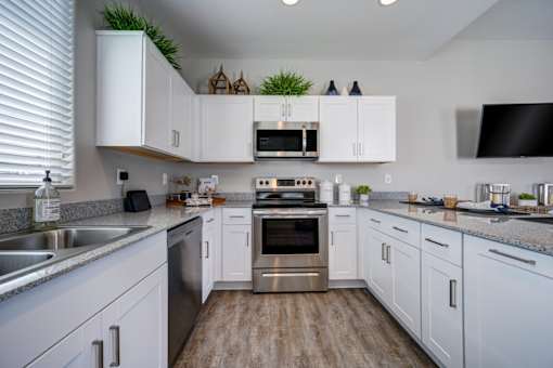 A kitchen with white cabinets and a wooden floor.