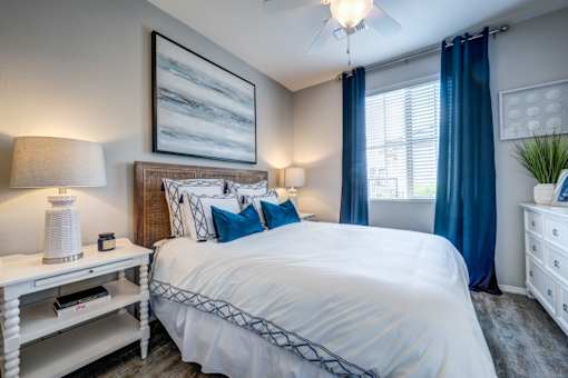 Bedroom with blue accent pillows and curtains at Vistoria On Camelback Apartments, Arizona, 85340
