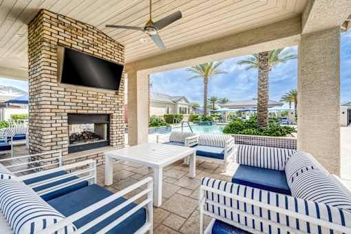 A patio with a fireplace and a television on the wall.