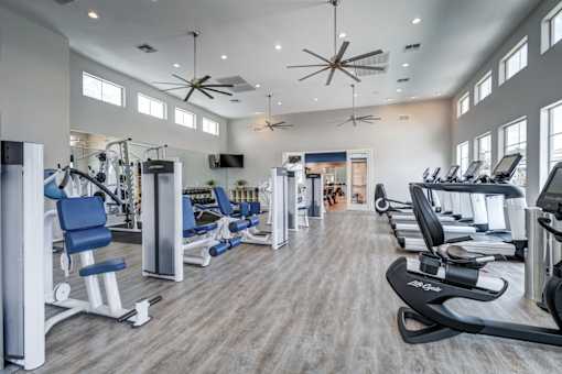 A spacious gym with a variety of equipment and a ceiling fan.