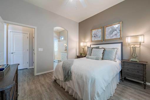 Master bedroom with upholstered headboard at Vistoria On Greenway Apartments, Surprise