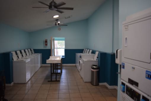 an empty laundry room with washing machines and a ceiling fan  at Somerset Apartments, Largo, FL, 33774