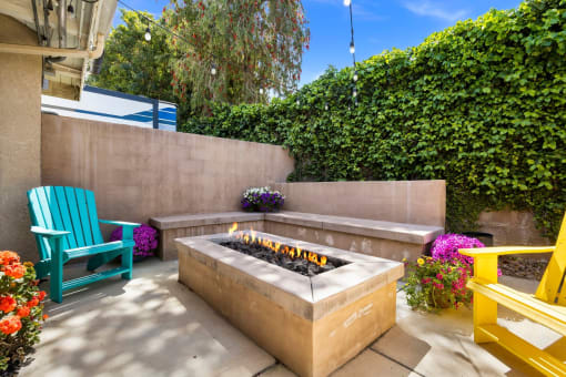a concrete fire pit with a concrete bench in front of it and a green hedge behind it