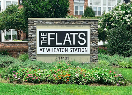 A sign that says "The Flats at Wheaton Station" in front of a building.