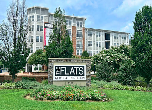 The Flats at Wheaton Station is a white building with a sign in front of it.