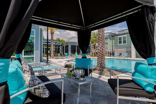 a swimming pool with blue chairs and tables at The Addison on Long Bayou Apartments, Florida