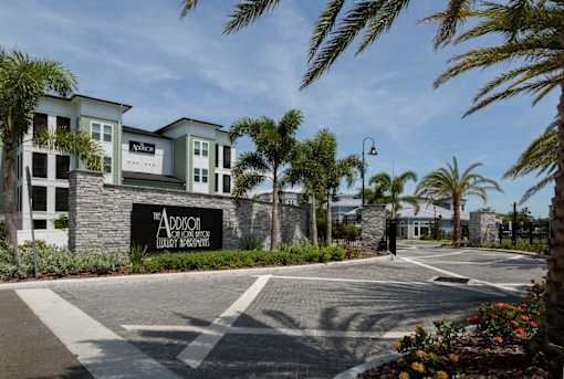 an empty parking lot in front of a building with palm trees at The Addison on Long Bayou Apartments, Seminole, Florida