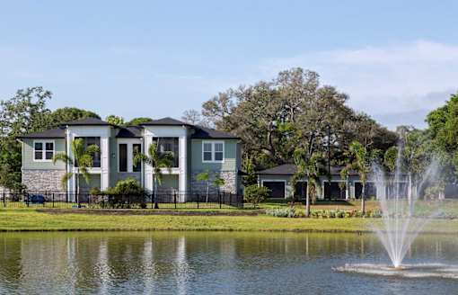 a fountain in the lake with houses in the background at The Addison on Long Bayou Apartments, Seminole, 33772