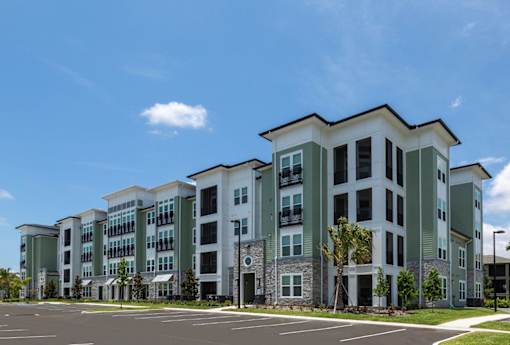 an exterior view of an apartment building with a parking lot at The Addison on Long Bayou Apartments, Seminole, FL, 33772