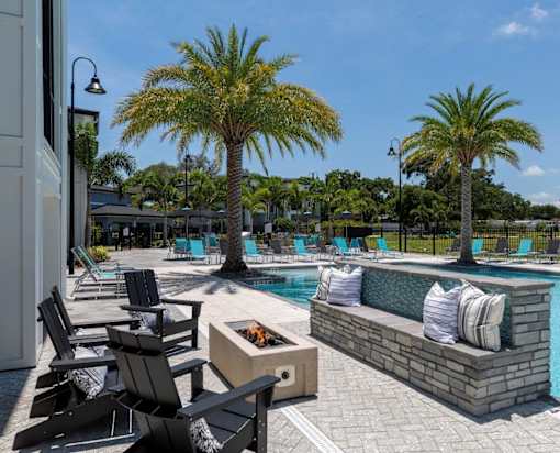 a swimming pool with chairs and a fire pit at The Addison on Long Bayou Apartments, Florida