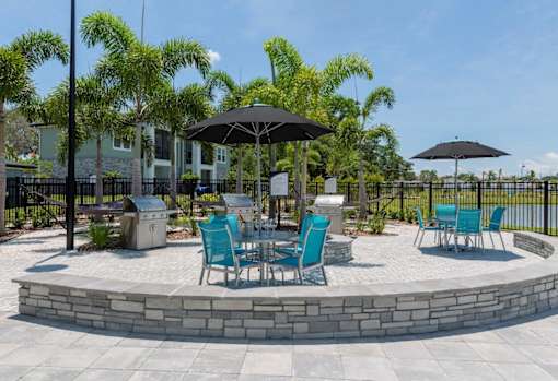 a patio with tables and chairs and umbrellas at The Addison on Long Bayou Apartments, Seminole, FL