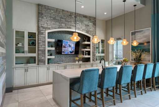 a kitchen with a bar and blue chairs at The Addison on Long Bayou Apartments, Seminole, FL, 33772
