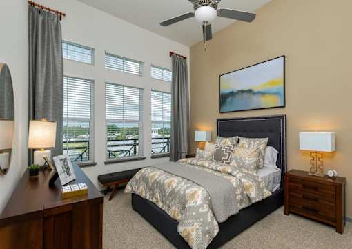 a bedroom with a large bed and a ceiling fan at The Addison on Long Bayou Apartments, Seminole, Florida