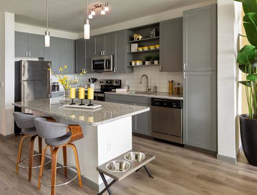 a kitchen with stainless steel appliances and gray cabinets at The Addison on Long Bayou Apartments, Seminole, 33772