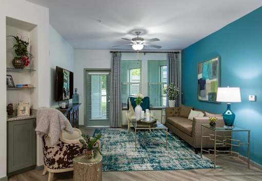 a living room with blue walls and a ceiling fan at The Addison on Long Bayou Apartments, Florida