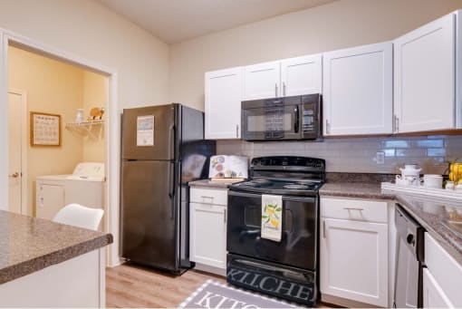 a kitchen with white cabinets and black appliances at Magnolia Village Apartments, Florida 32207