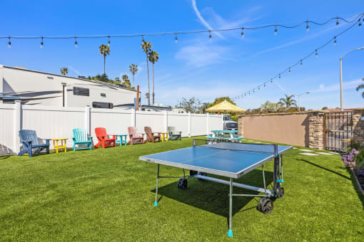 a backyard with a ping pong table and lounge chairs
