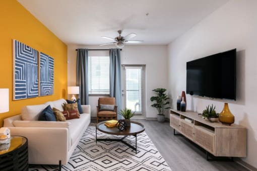 A living room with a white couch, a coffee table, a TV, and a plant at Enclave at 3230 Apartments, South Daytona, Florida