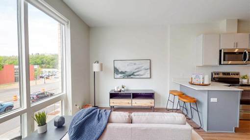A modern living room with a grey couch and a blue blanket on it. at The Arlow on Kellog, St. Paul, 55102
