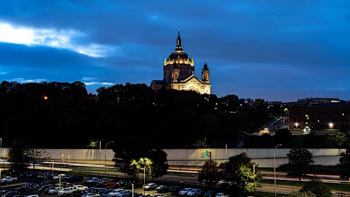 A large white building with a golden dome is lit up at night.