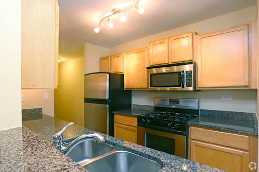 A kitchen with a sink, stove, and microwave.