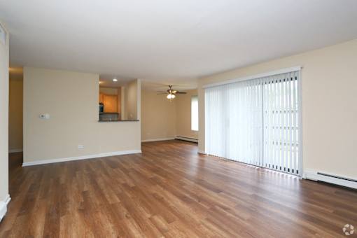 A room with wooden flooring and a window with blinds.