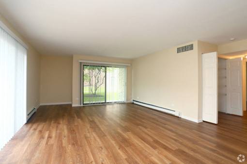 A room with wooden floors and a sliding glass door leading outside.