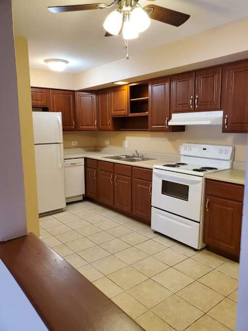A kitchen with white appliances and brown cabinets.