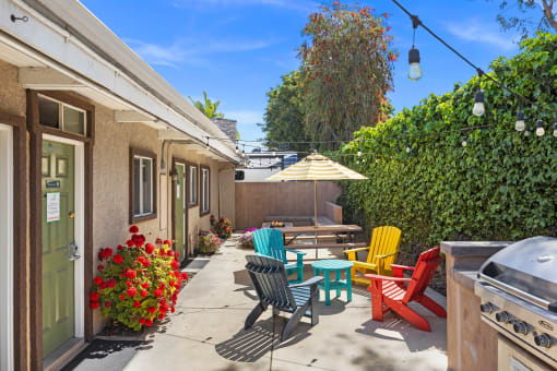 a patio with colorful chairs and an umbrella