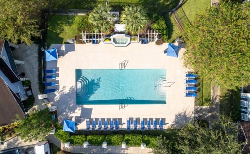 arial view of a swimming pool with chaise lounge chairs and trees in the background at Magnolia Village Apartments, Jacksonville, Florida